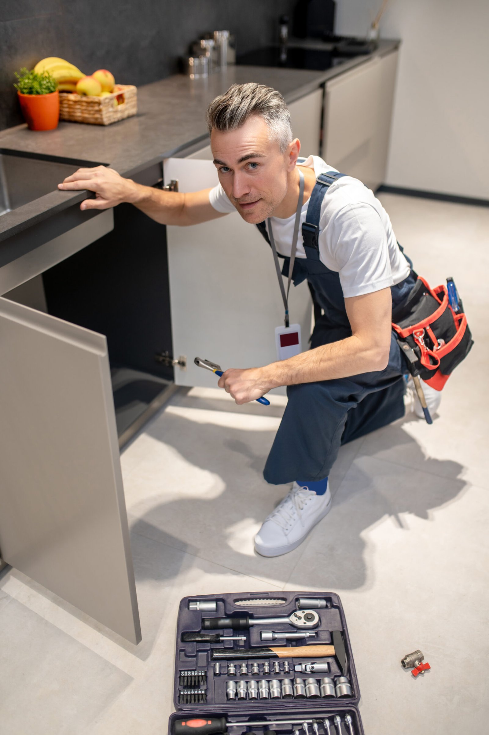 Top view of man crouching near sink looking at camera